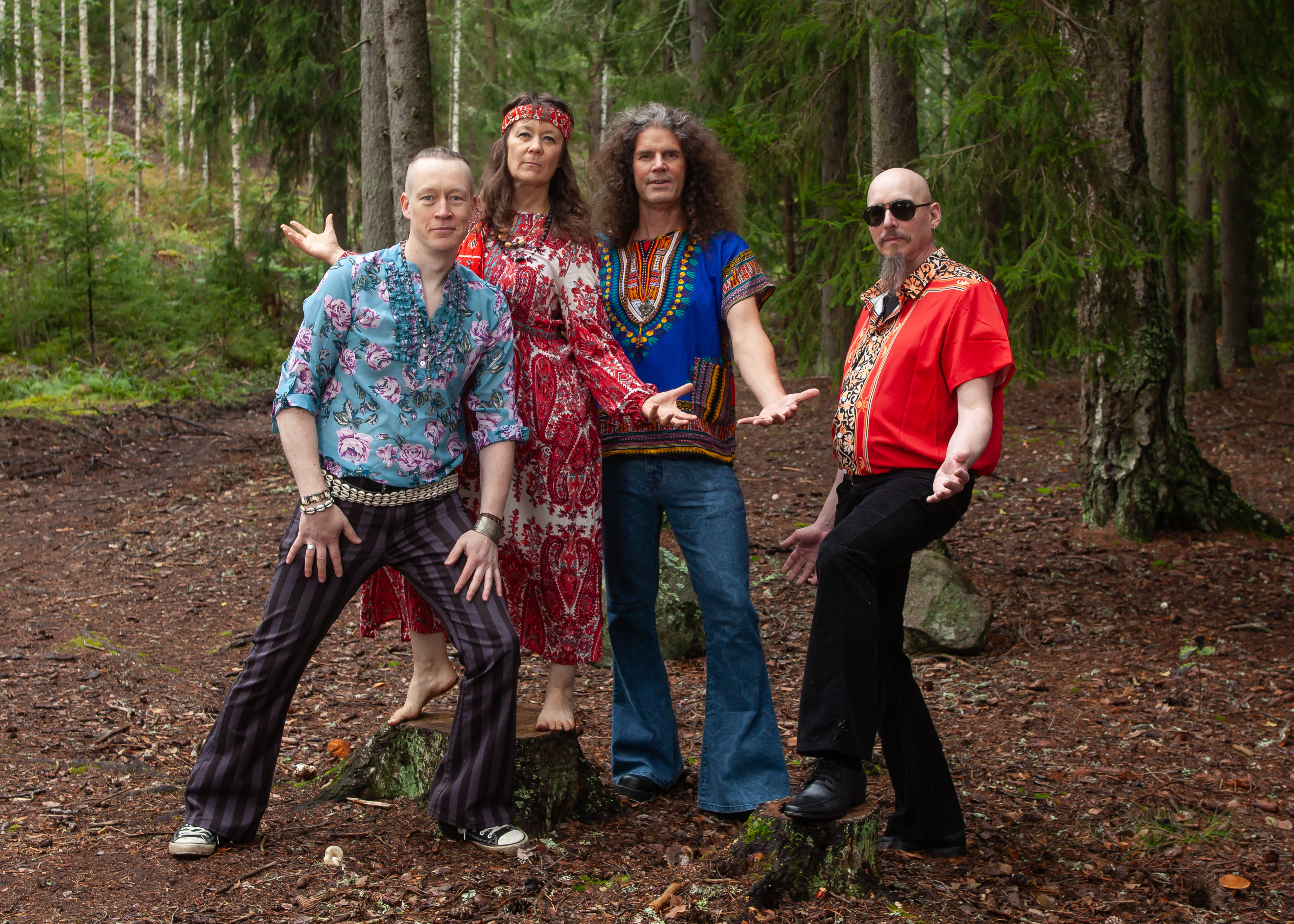 The four members of Aamunkoite in colourful outfits in a forest.